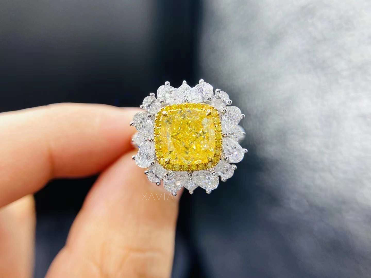 Close-up of Velouria cushion-cut fancy yellow diamond ring with pear-shaped white diamond halo in luxury high-polish metal