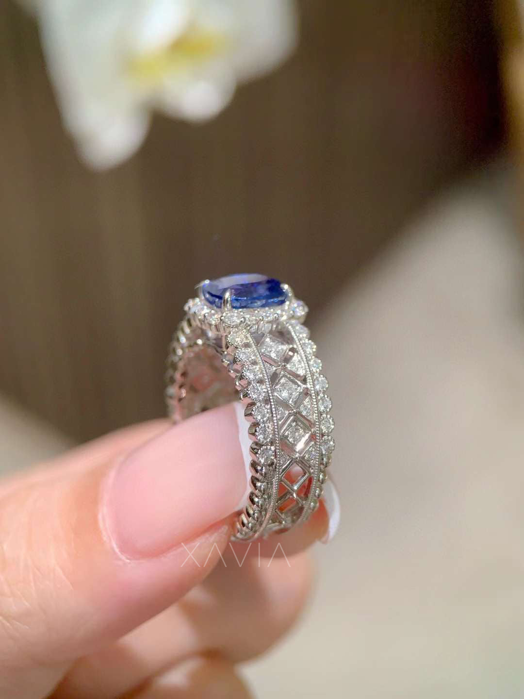 detailed view of geometric lattice diamond band structure with pavé diamond rows supporting cushion sapphire halo center stone