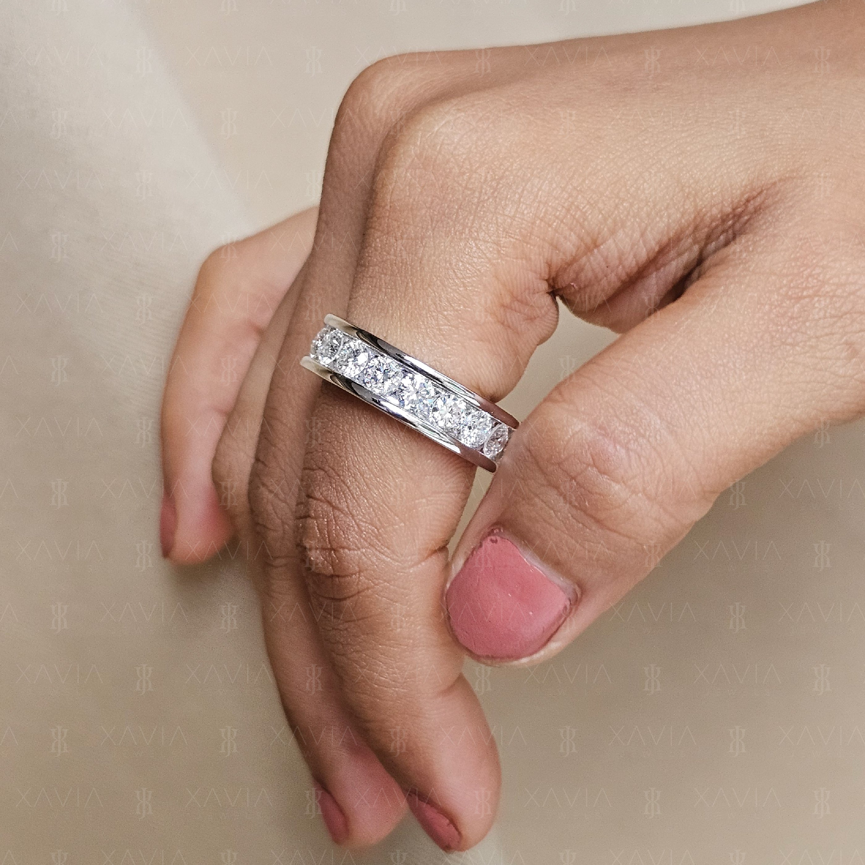Wide channel-set round lab-grown diamond eternity band worn on hand featuring polished white metal edges and continuous brilliant diamond row