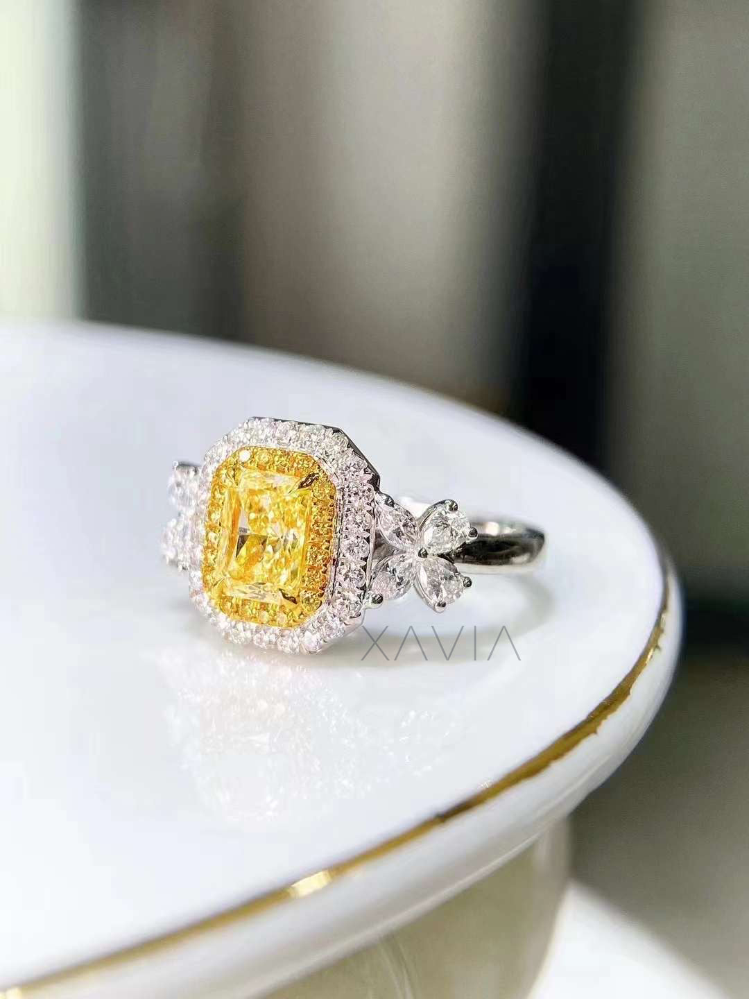 cushion cut fancy yellow diamond halo ring with floral marquise side stones worn on model’s hand for engagement styling