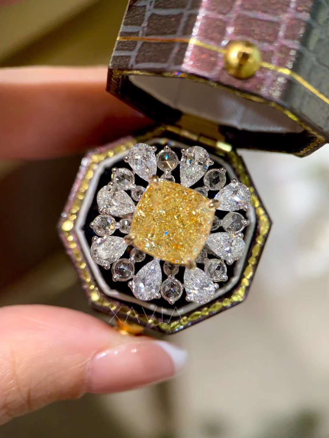 lifestyle image showing fancy yellow cushion diamond ring with pear halo diamonds worn with luxury handbag and diamond bracelet ensemble