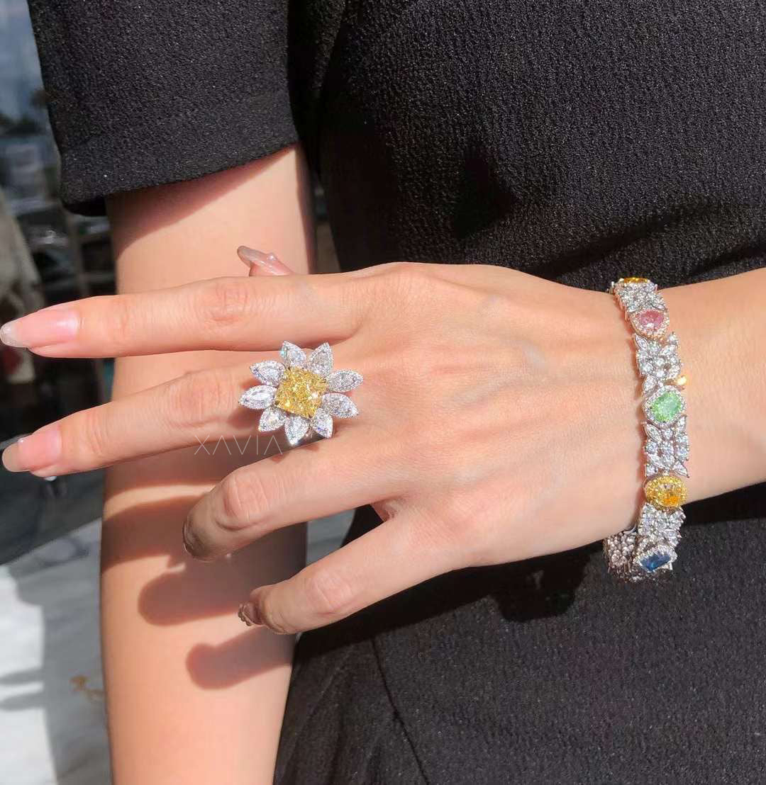radiant fancy yellow diamond floral halo cocktail ring worn on model’s hand with diamond bracelet in sunlight