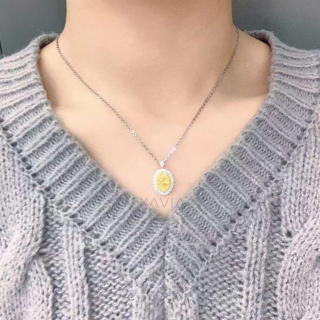 oval fancy vivid yellow diamond halo pendant on silver chain worn with grey sweater, elegant fine jewelry look